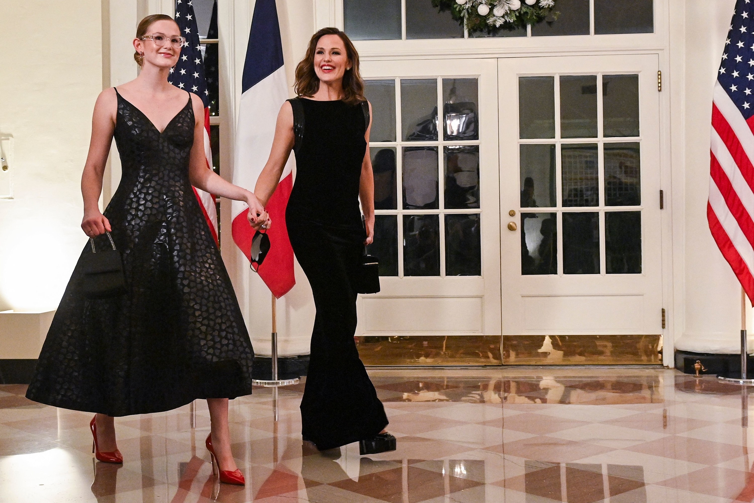 Violet and Jennifer holding hands and walking, with the US flag visible