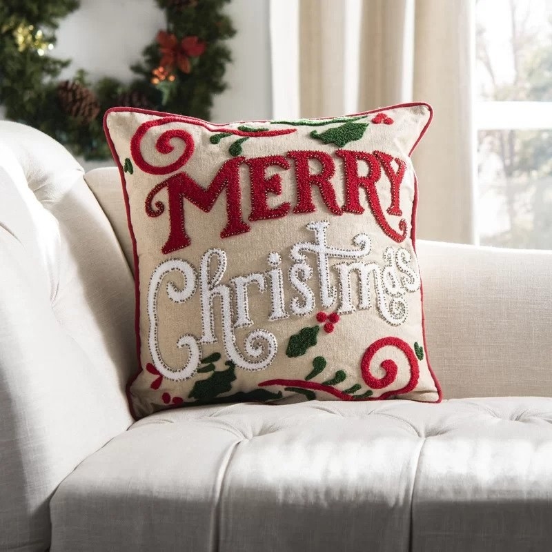 Beige decorative pillow that says Merry Christmas in red &amp;amp; white