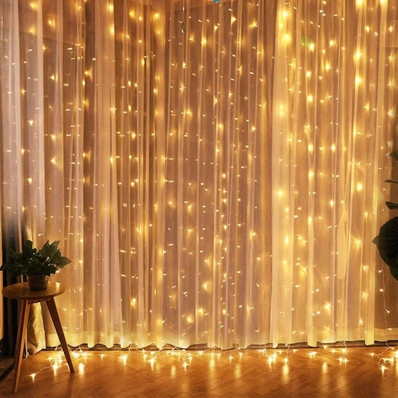 Yellow fairy lights behind sheer white curtain