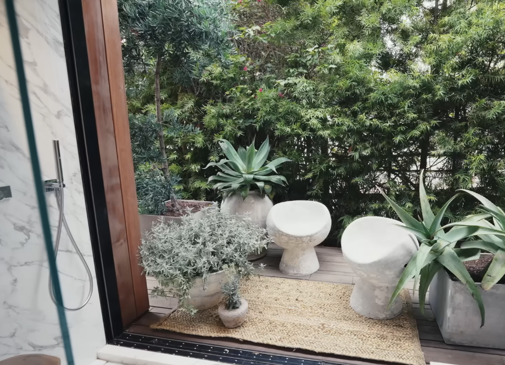 outdoor sitting area with marble chairs, various plants, and a rug