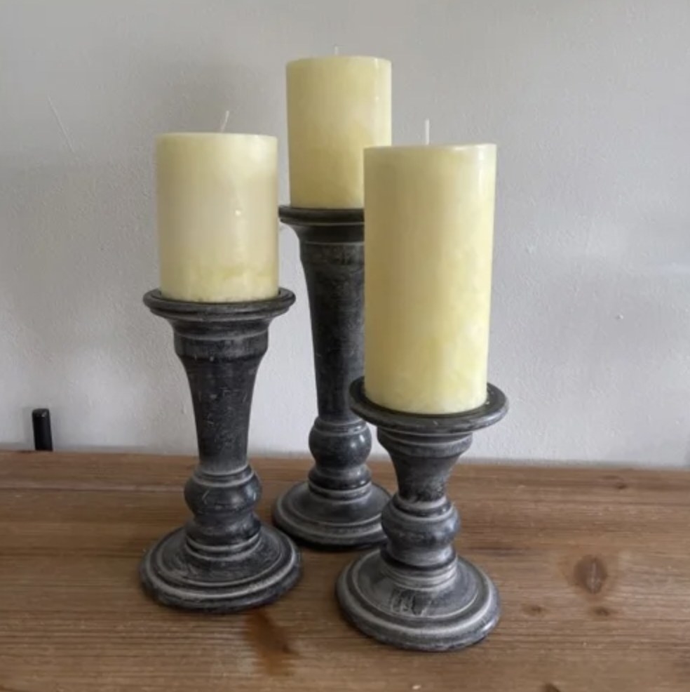 Reviewer&#x27;s photo of three of the pillar candles set on decorative holder stands