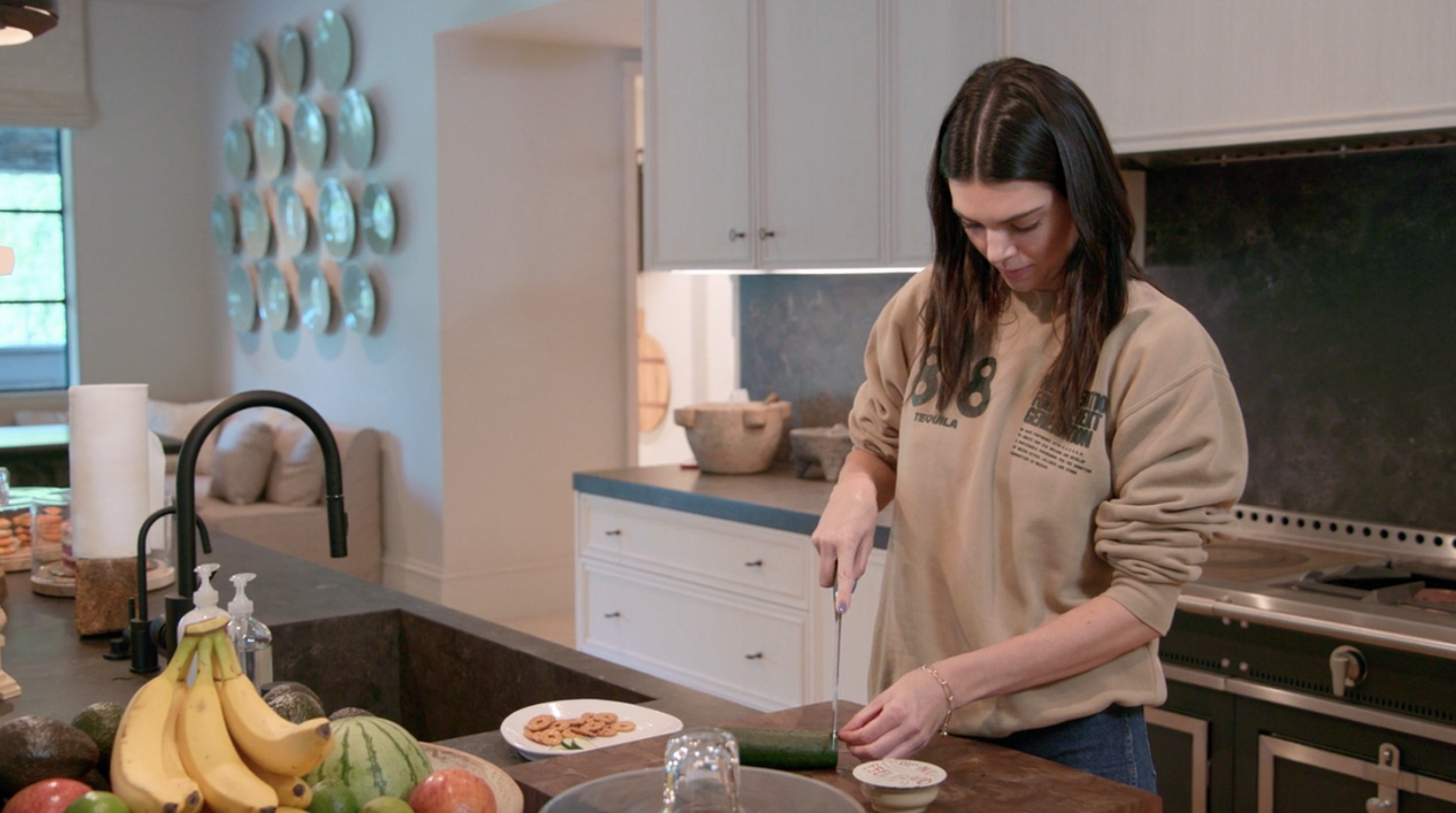 Kendall in a kitchen cutting a cucumber