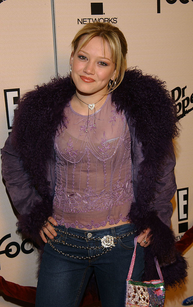 hilary wearing low-rise jeans and a fuzzy-trimmed coat