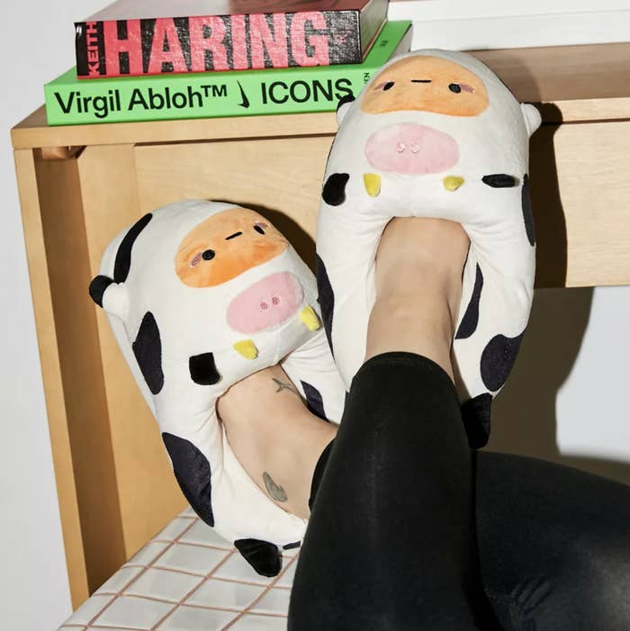 A person kicking their feeet up while wearing the cow slippers