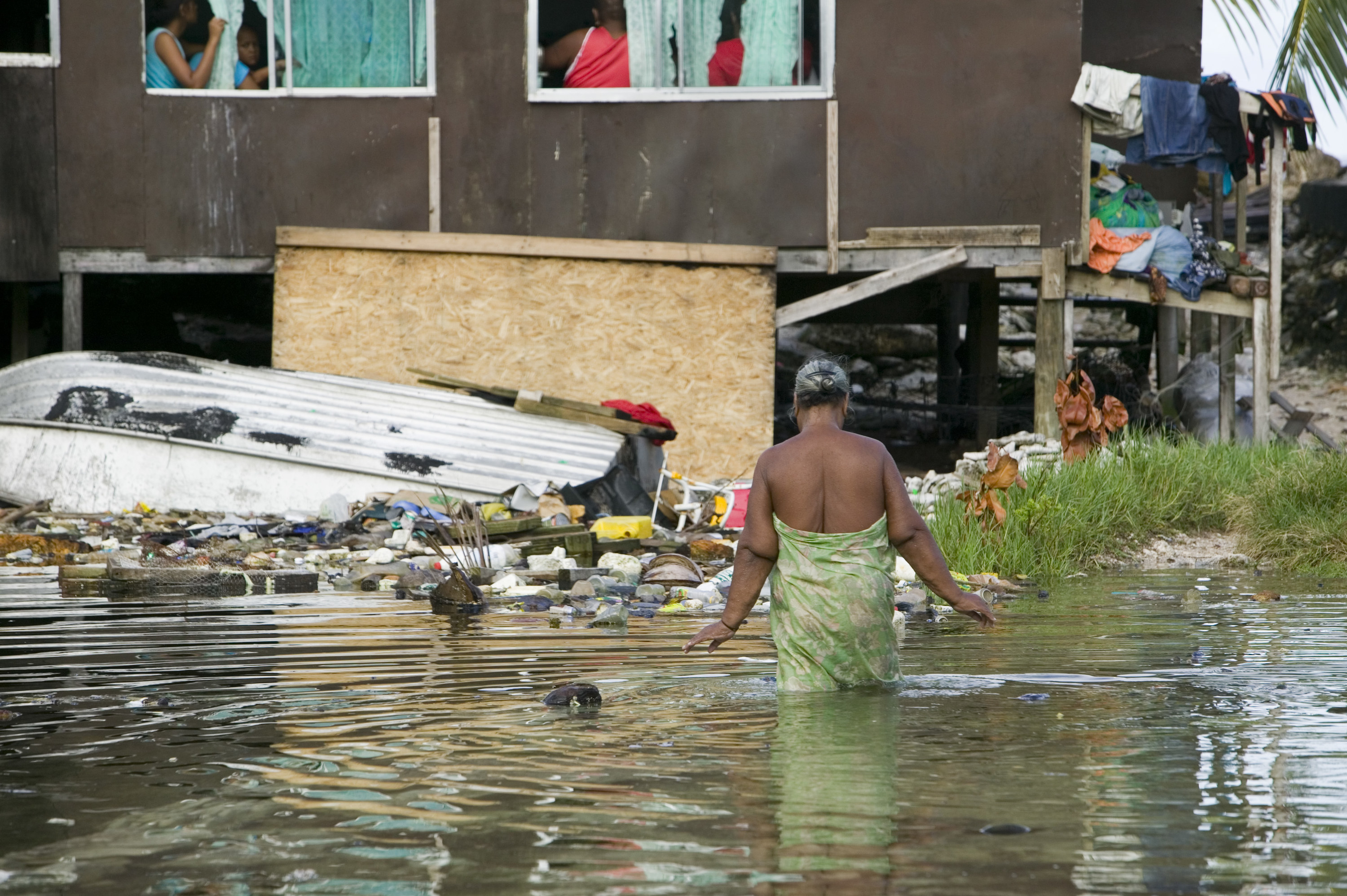 A woman in Tuvalu wades through knee-deep flooding in Funafuti