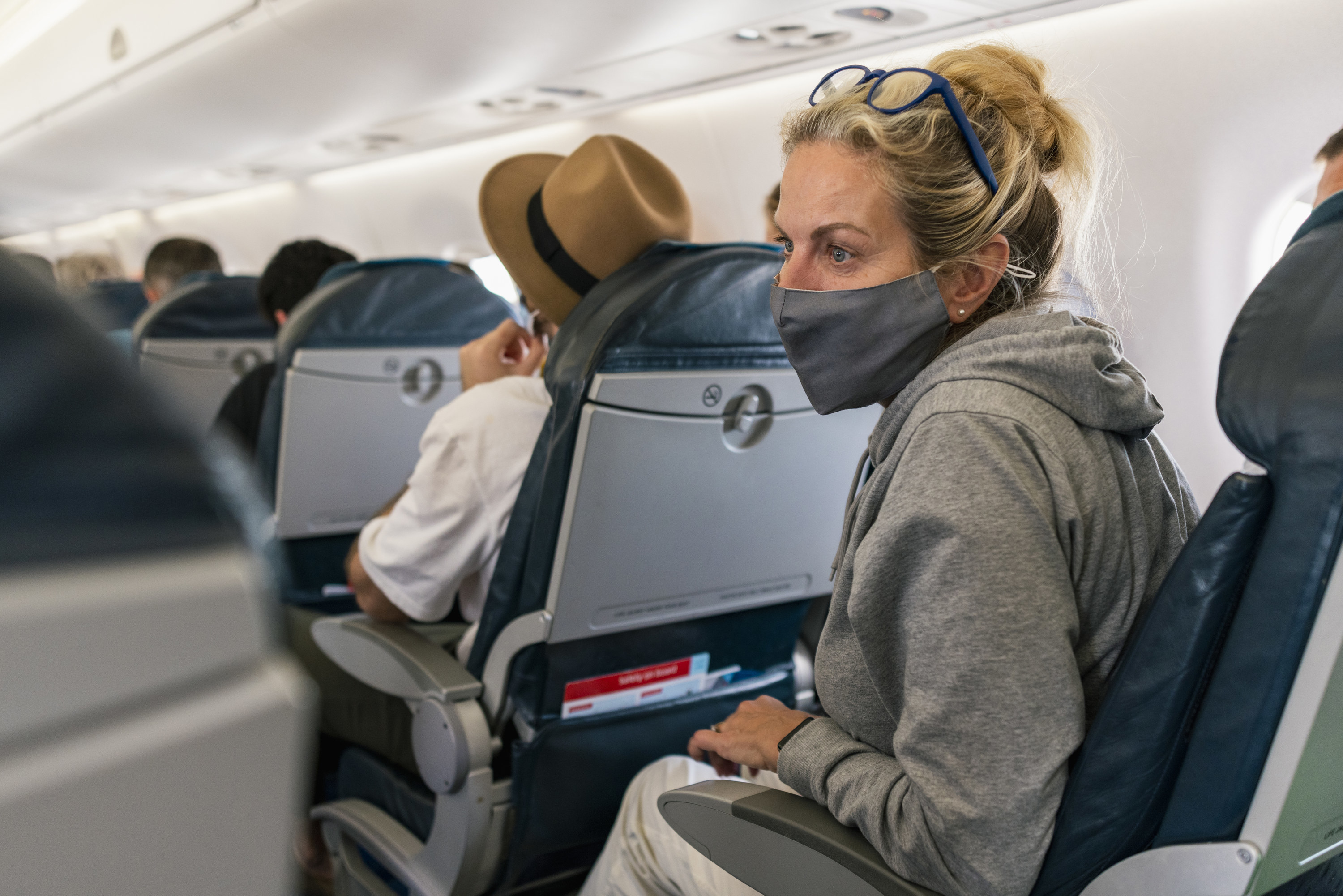 Woman sitting on a plane wearing a protective face mask
