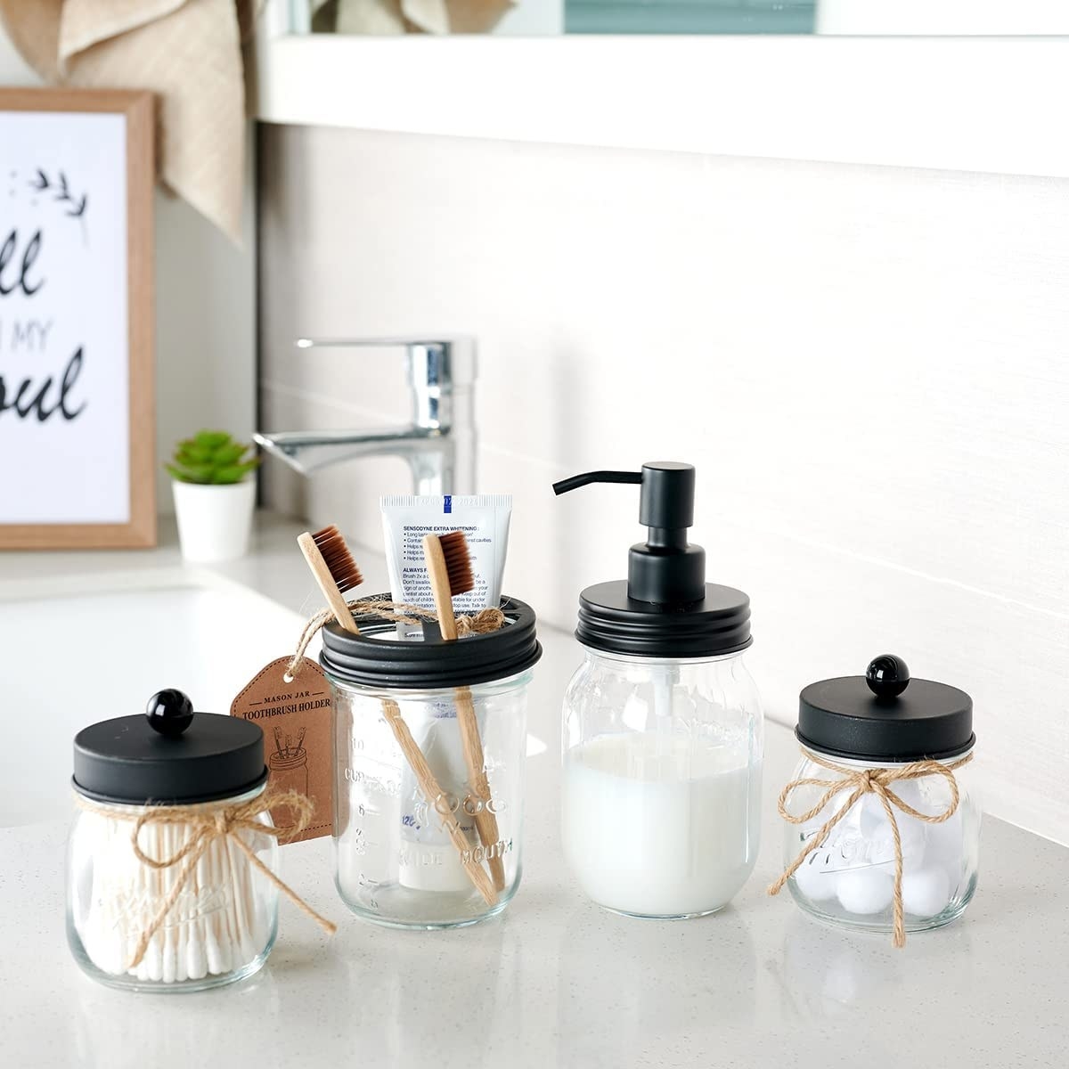The four mason jars with black tops. One has a soap dispenser, another is holding two tooth brushes, and two smaller jars have easy-to-lift tops filled with cotton balls and swabs