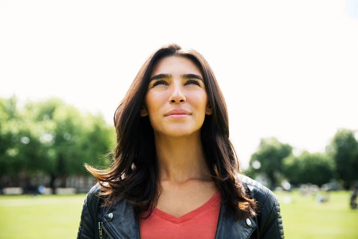 A woman looks up with a hopeful expression in a park