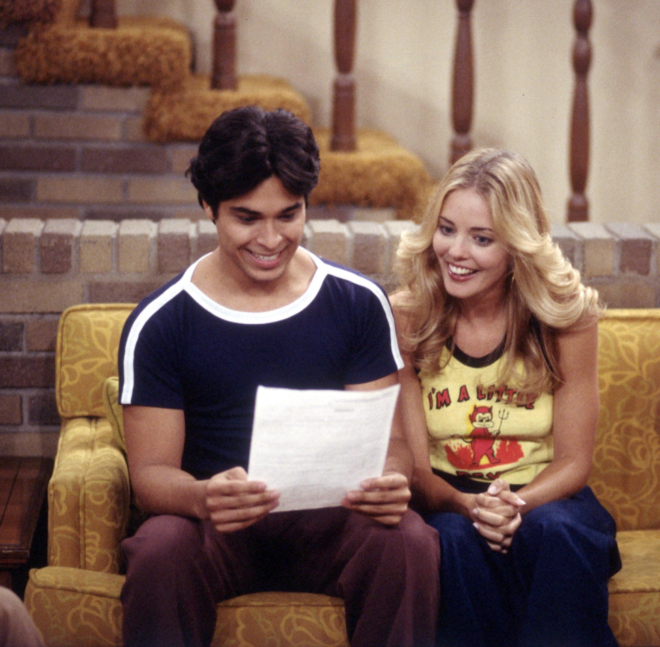Laurie and Fez looking at a piece of paper and smiling