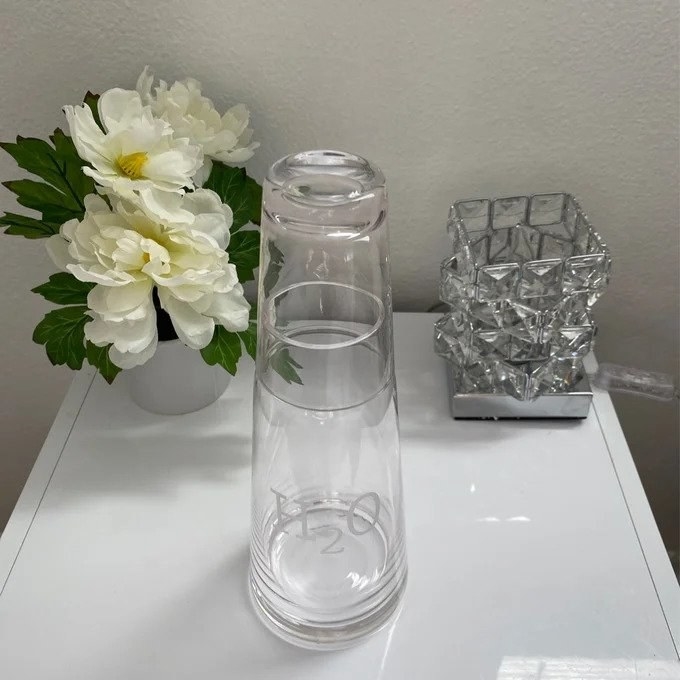 a reviewer photo of the glass bedside water carafe that says H2O in etching, on white end table