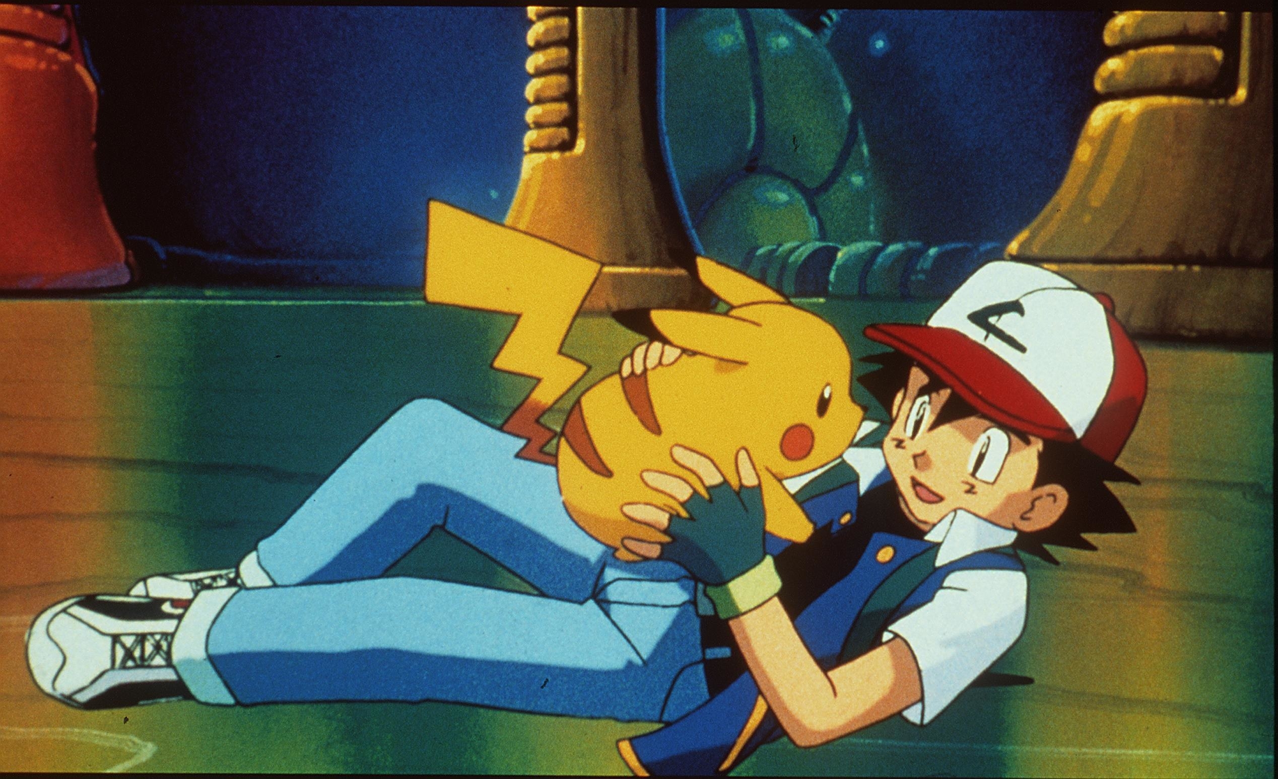 Pikachu being picked up by Ash Ketchum who is on the ground
