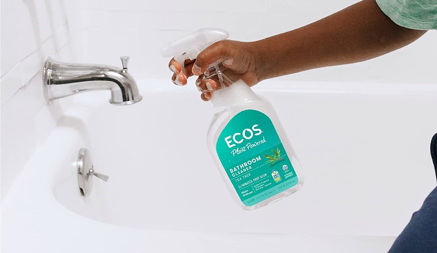 model sprays a bottle of ecos plant powered bathroom cleaner on tub
