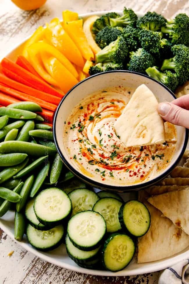 A bowl of hummus with vegetables for dipping.