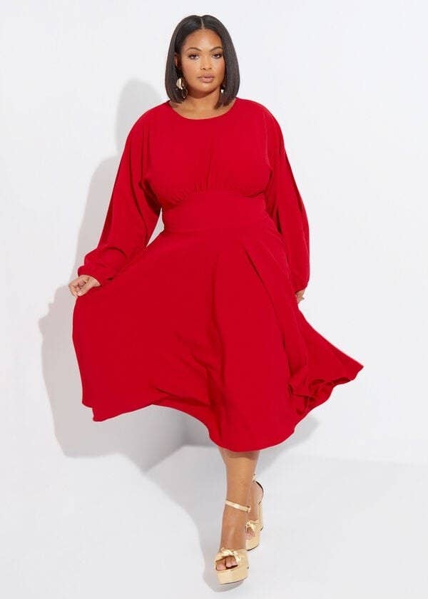 model in flowy red midi dress with long sleeves with split hems down their center