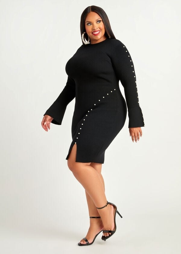 model in a black knit knee length long sleeve dress with pearl accents across the hip and down one sleeve