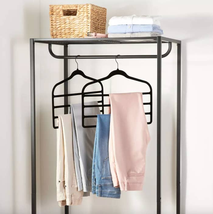 the black hangers with several pairs of pants hanging on a black clothing rack