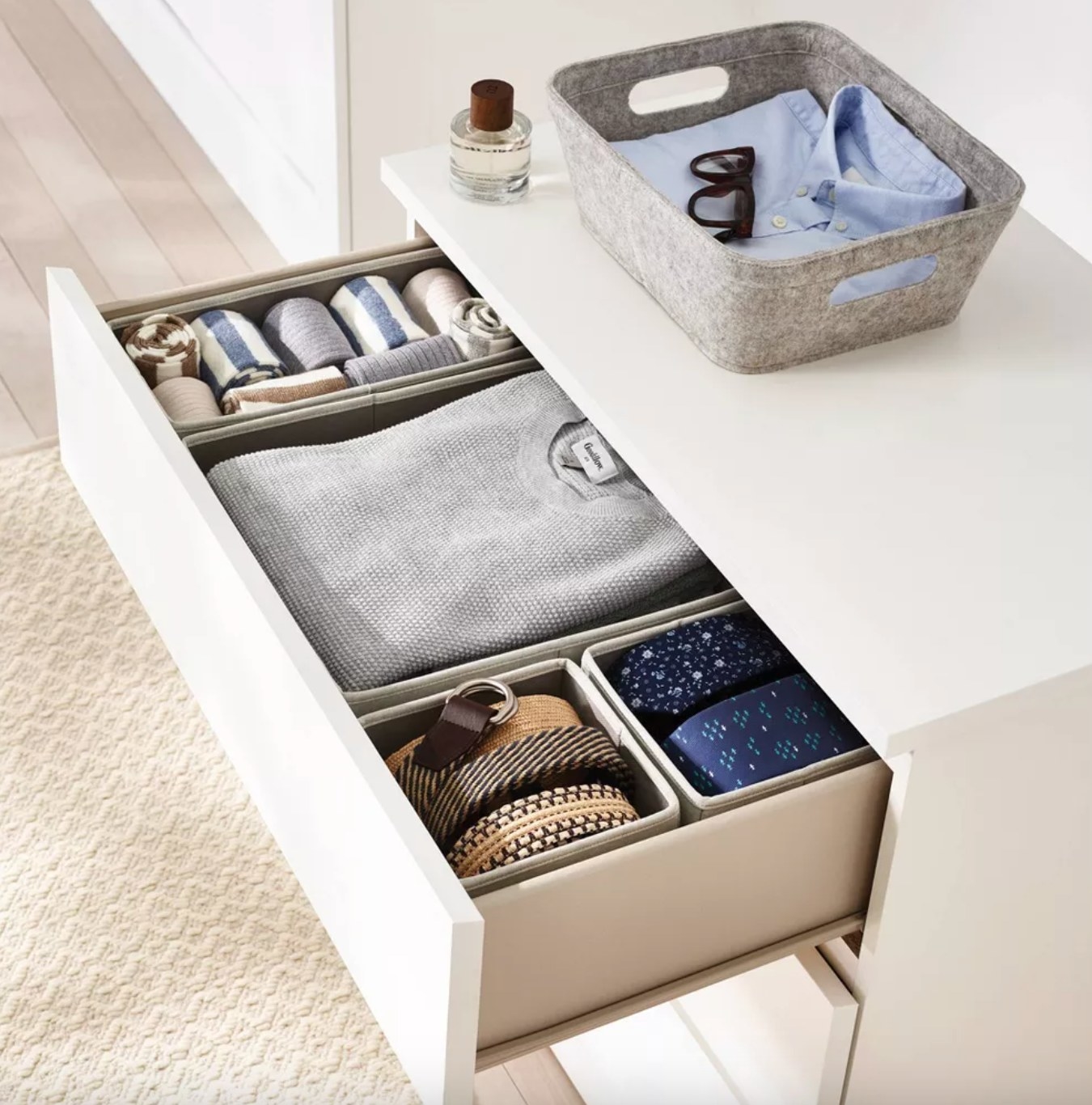 a white drawer open to show the grey organizers holding sweaters and accessories