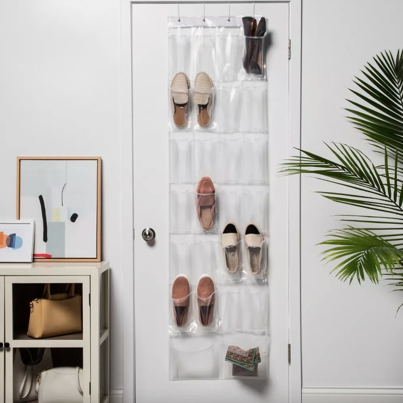 the clear organizer hanging over a door with several shoes in the pockets, in a decorated living space