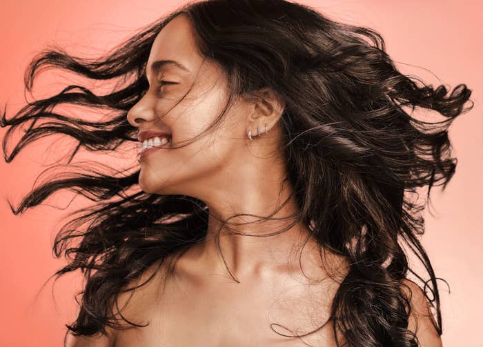 A woman flipping her glossy, wavy hair.