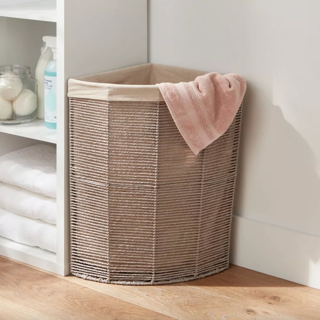 the lined tan wicker hamper in the corner of a decorated laundry area