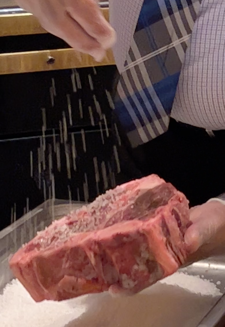 The chef sprinkles a layer of salt on the steak