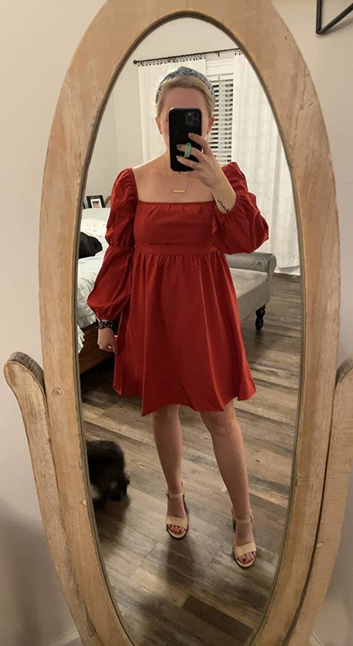 Reviewer wearing puff-sleeve mini dress in red with tan heels