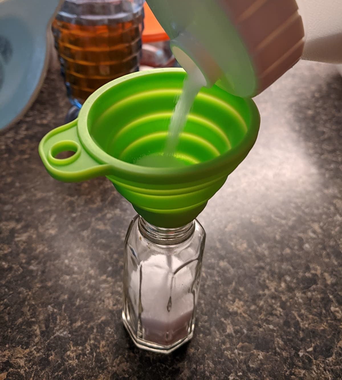 Reviewer refilling salt shaker using green funnel