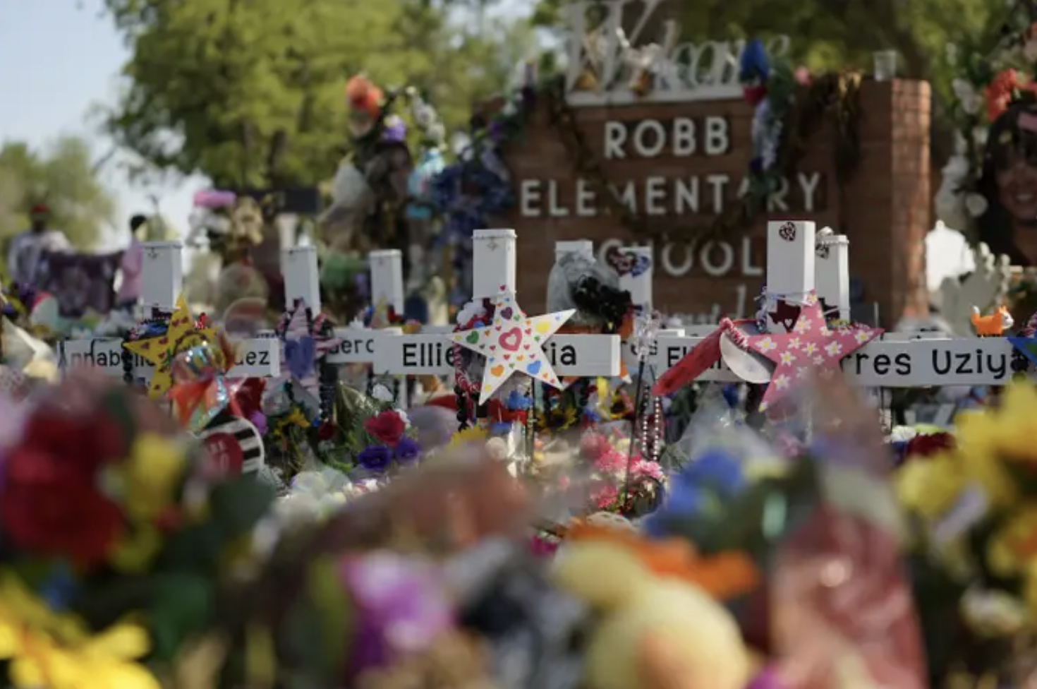 Crosses with victims&#x27; names are decorated in front of the Robb Elementary School sign
