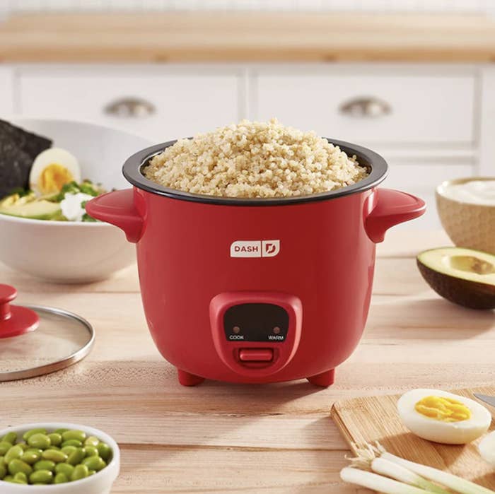 the rice cooker on a wooden counter surrounded by food