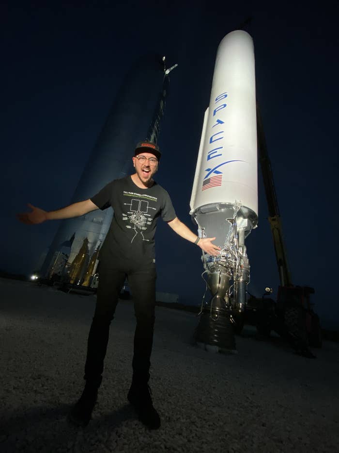Everyday Astronaut YouTuber Tim Dodd standing with his arms outstretched in front of a rocket