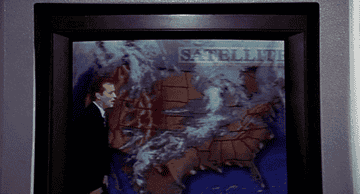 Bill Murray pretending to blow a storm away on a weather map in Groundhog Day