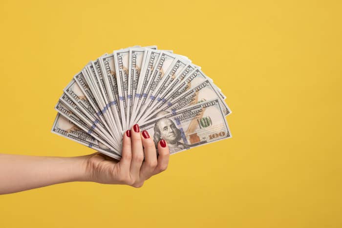 woman holding hundred-dollar bills fanned out