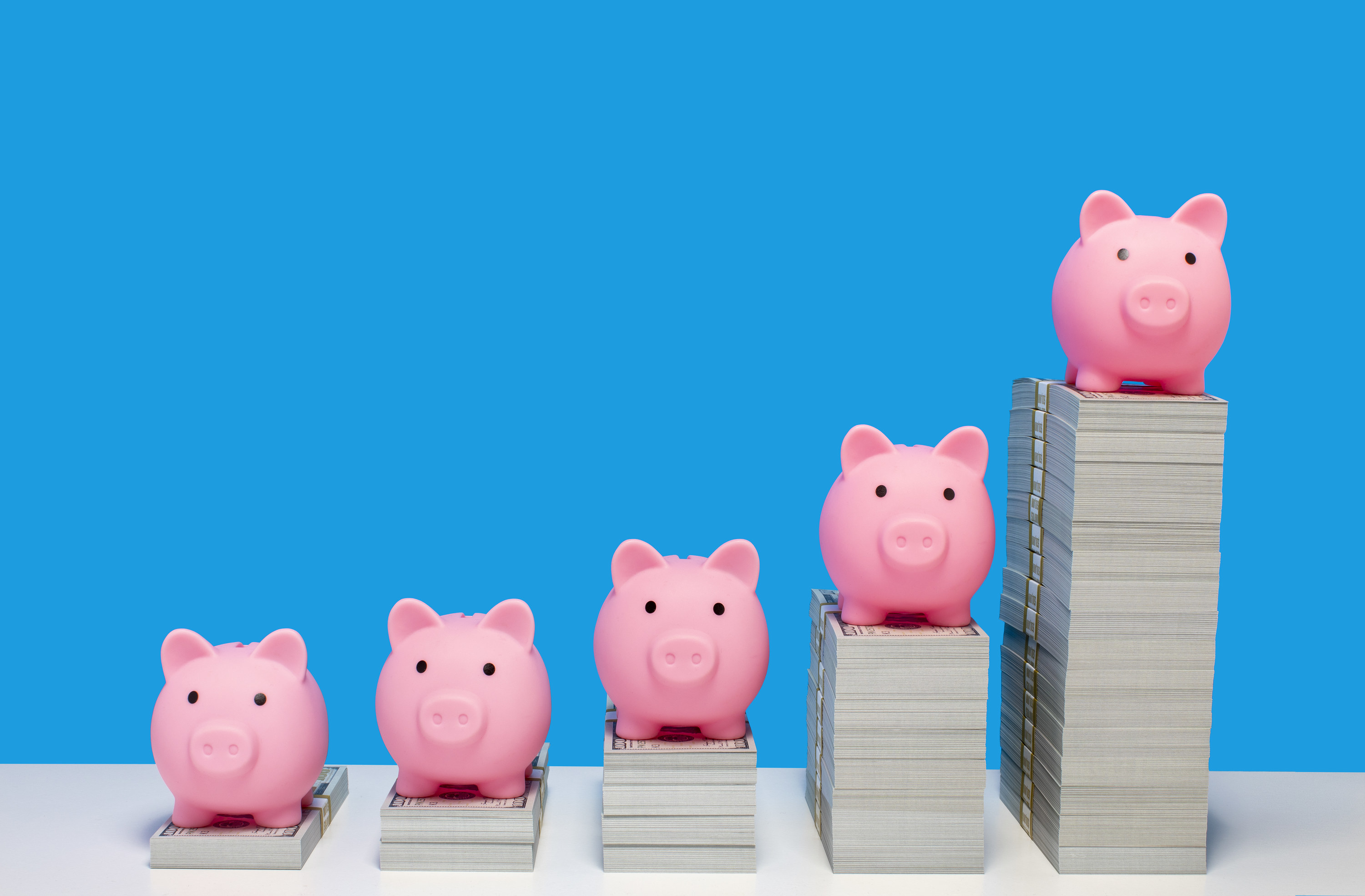 piggy banks on increasingly tall stacks of cash