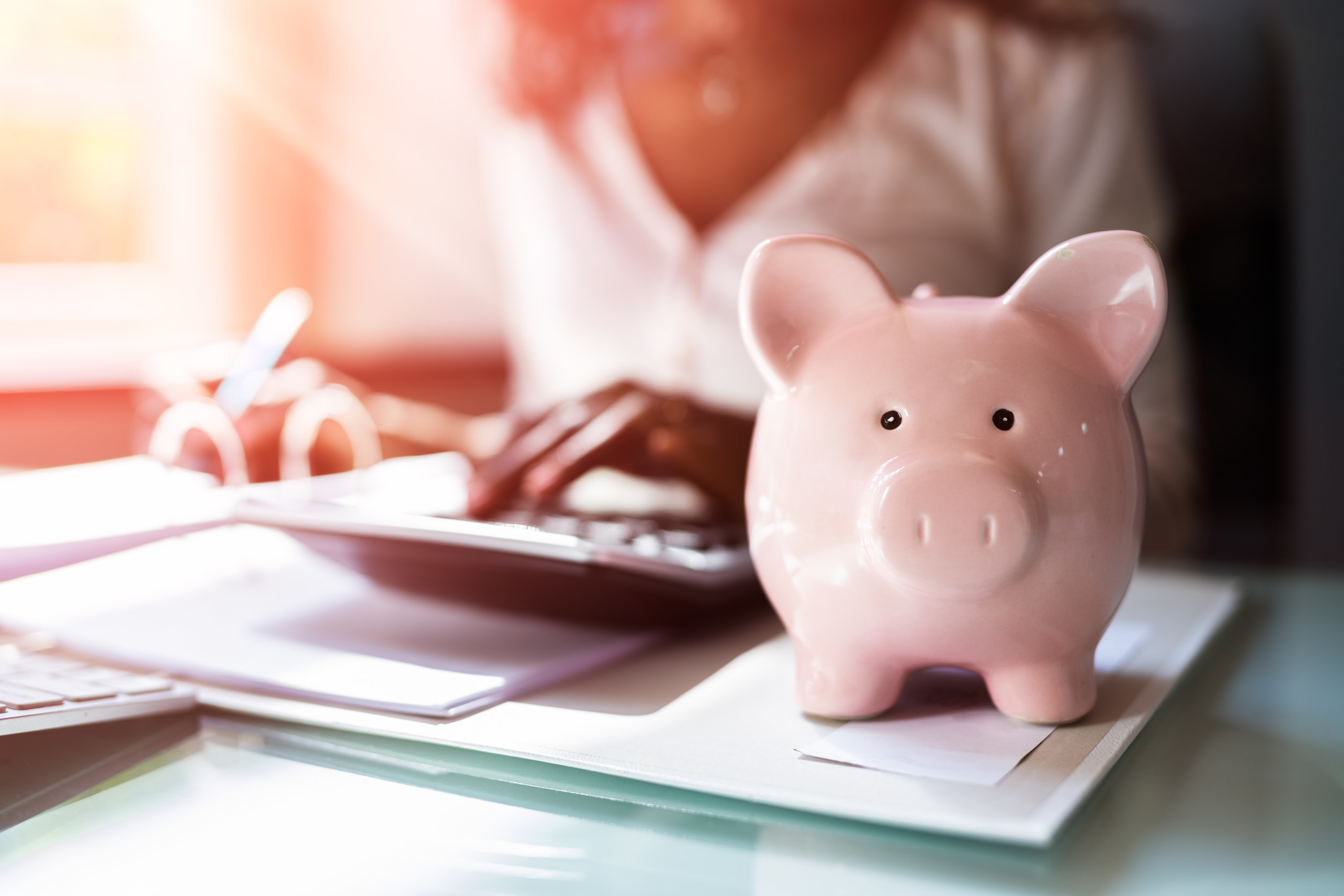 person with a calculator and a piggy bank