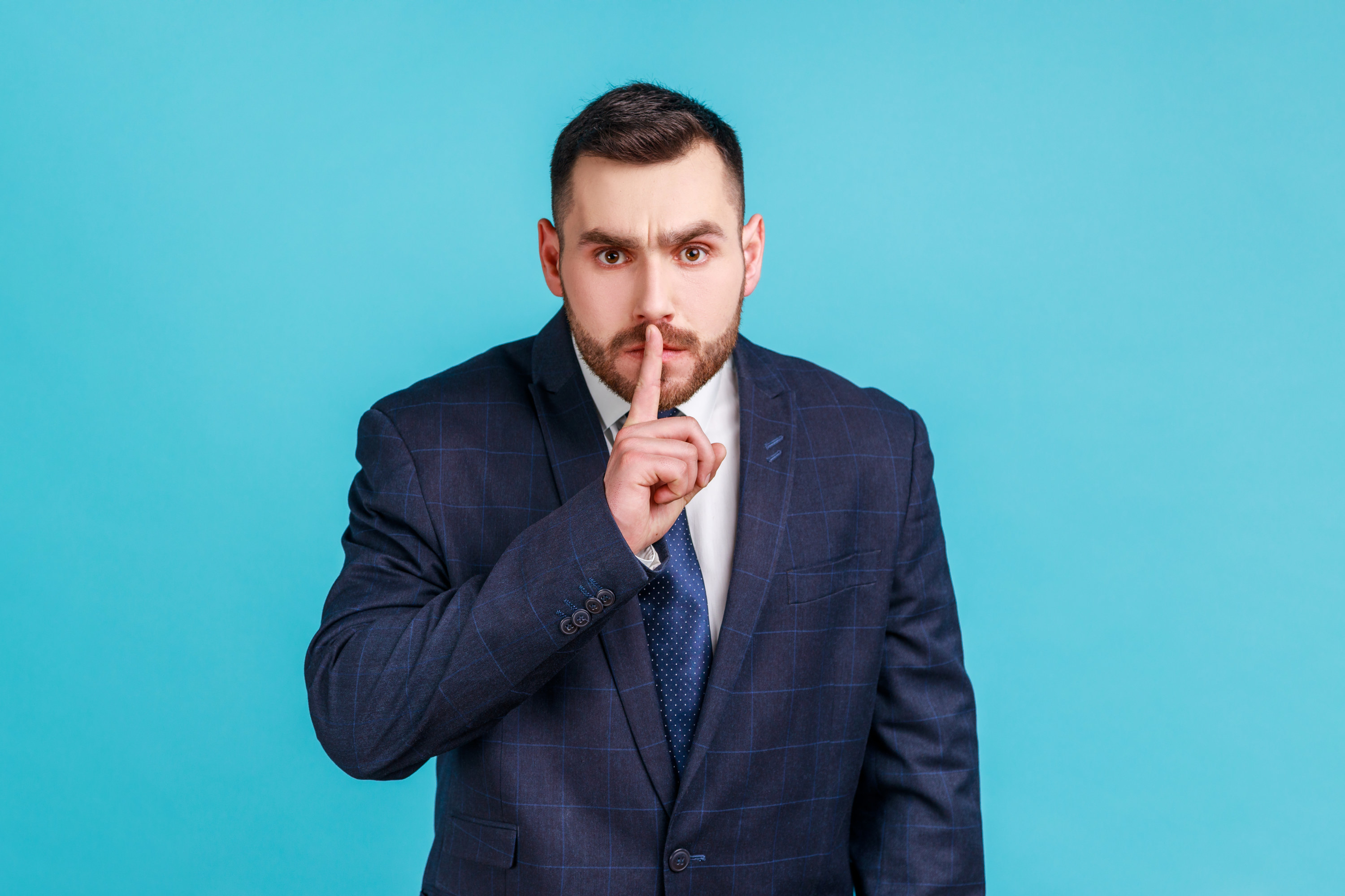 businessman with his finger over his mouth and shushing