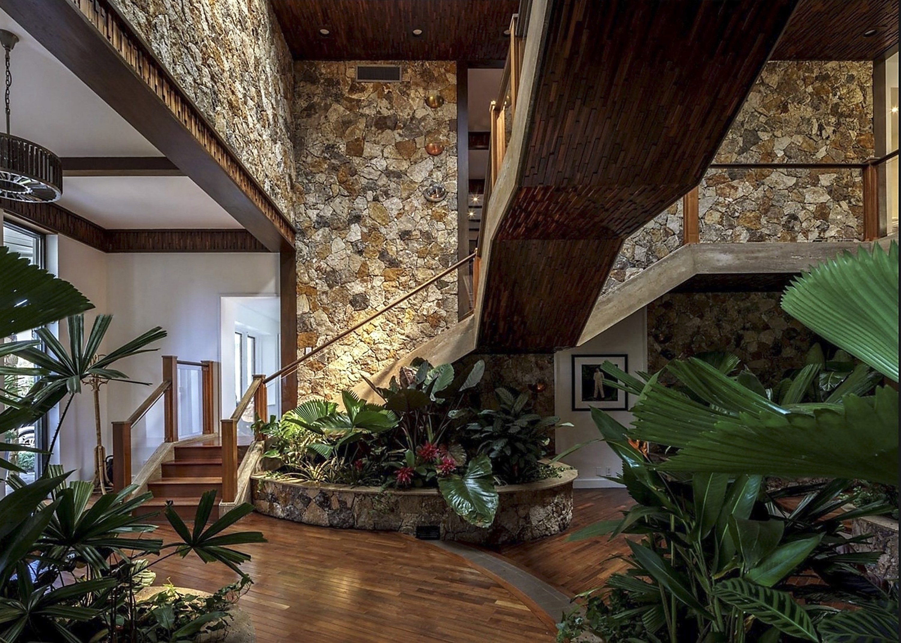 Many plush plants surrounding a spiral staircase and stone wall paneling
