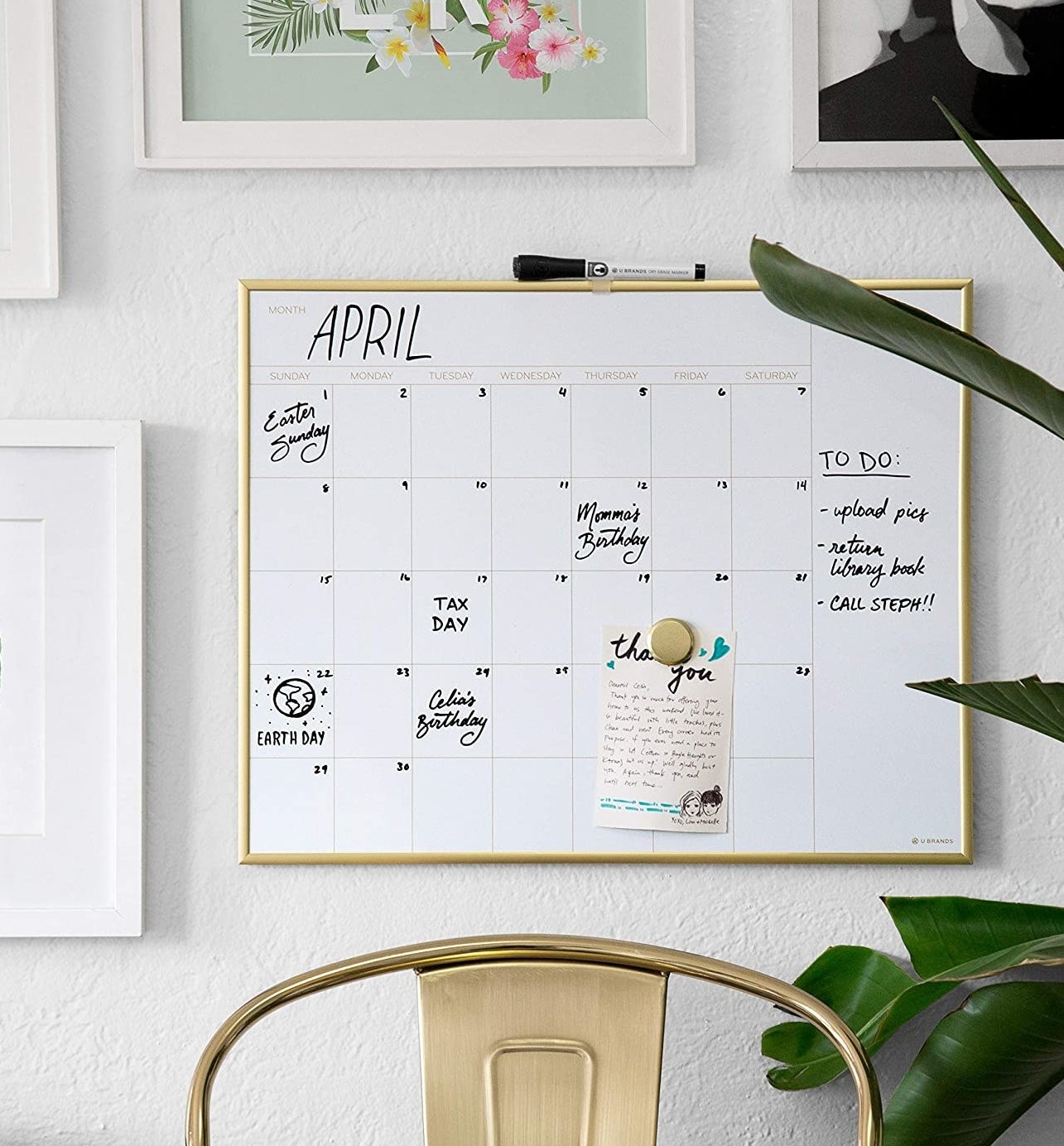 a gold rimmed dry erase calendar on a wall