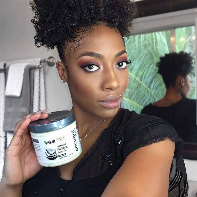 model with curly hair holding the product jar