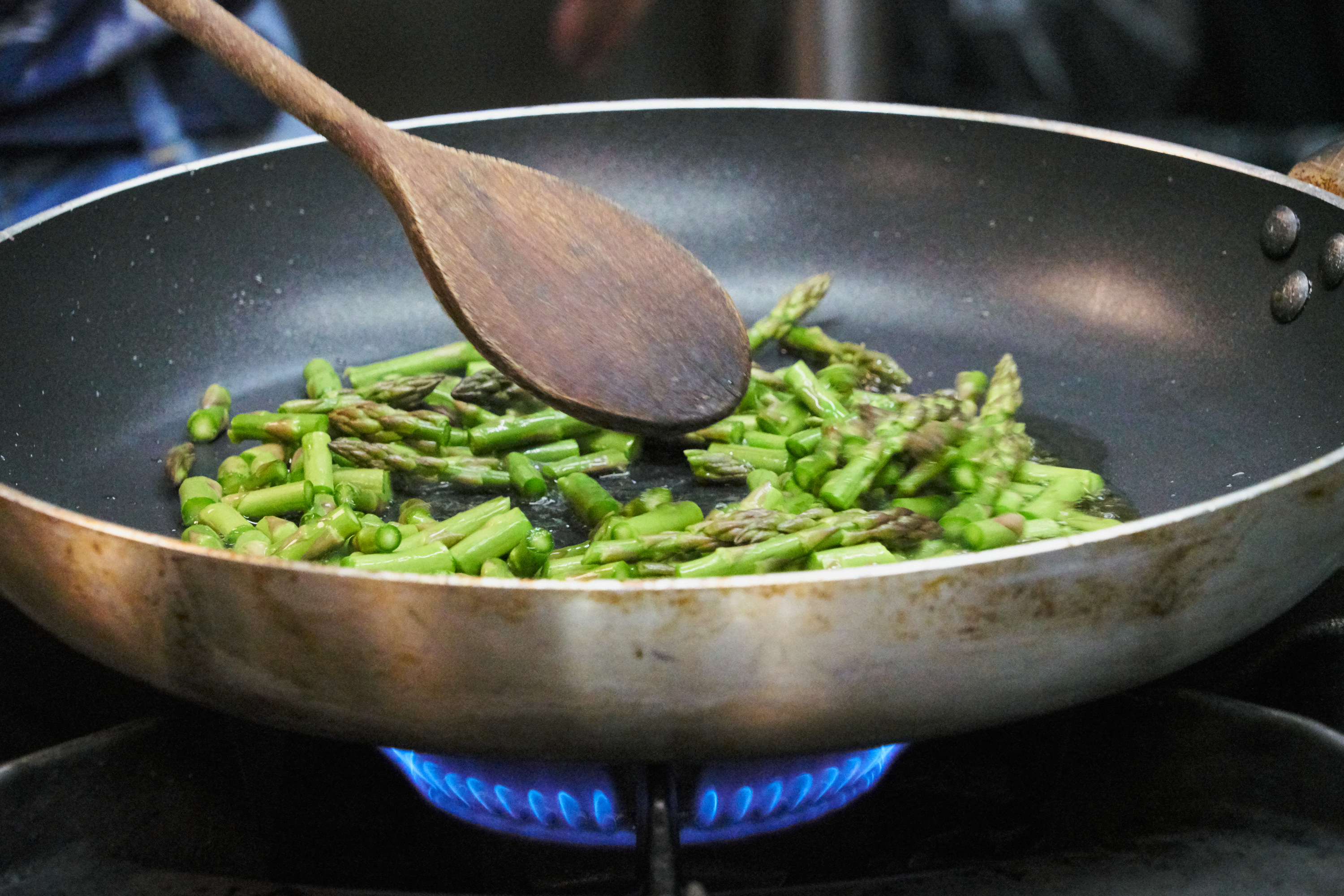 asparagus in a saute pan cooking on a stovetop