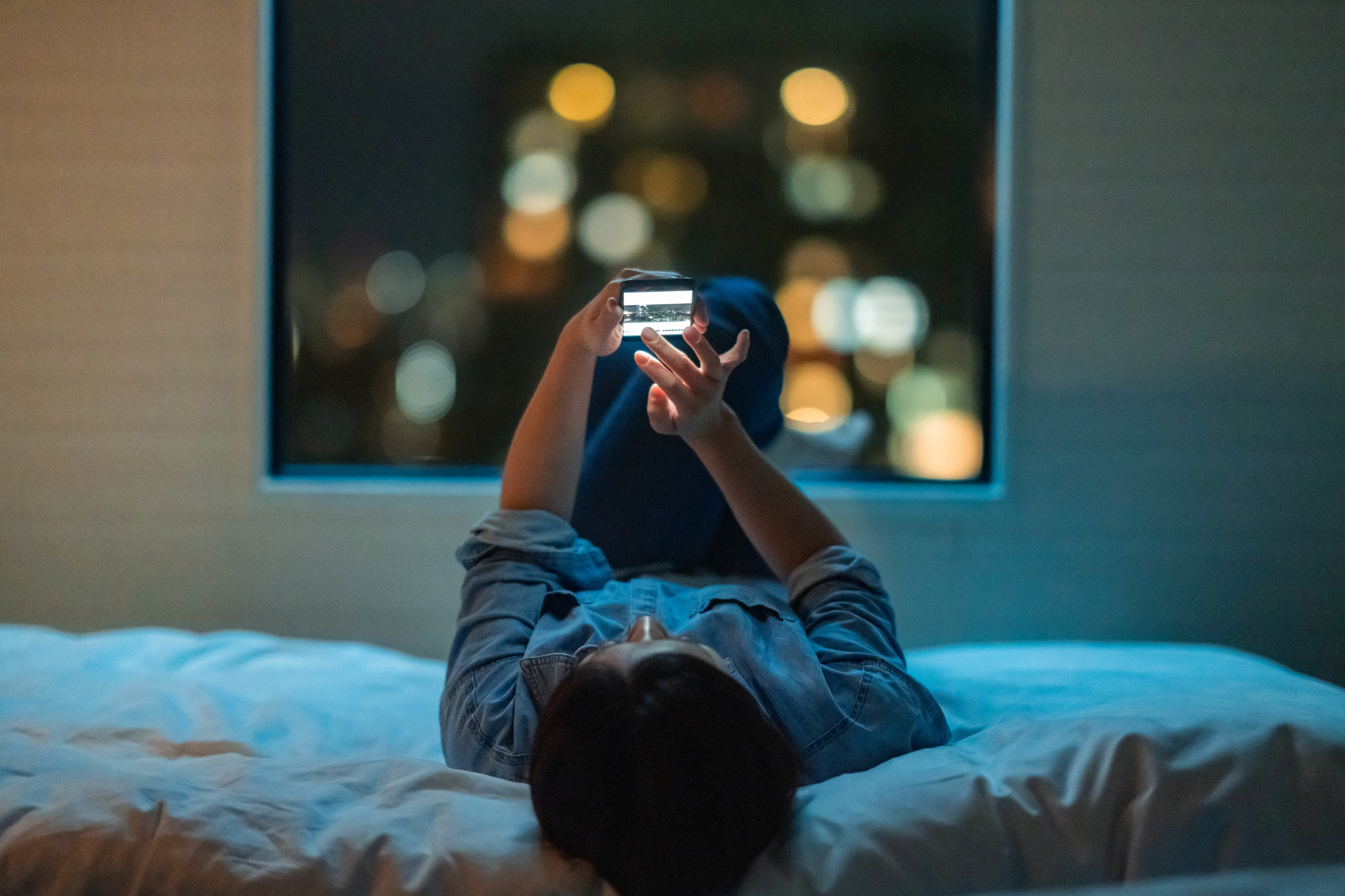 Person lying on a bed and looking at a phone