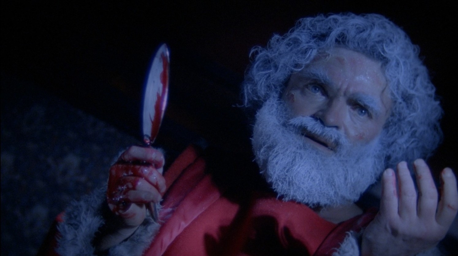 A fake Santa Claus holds up a bloody razor