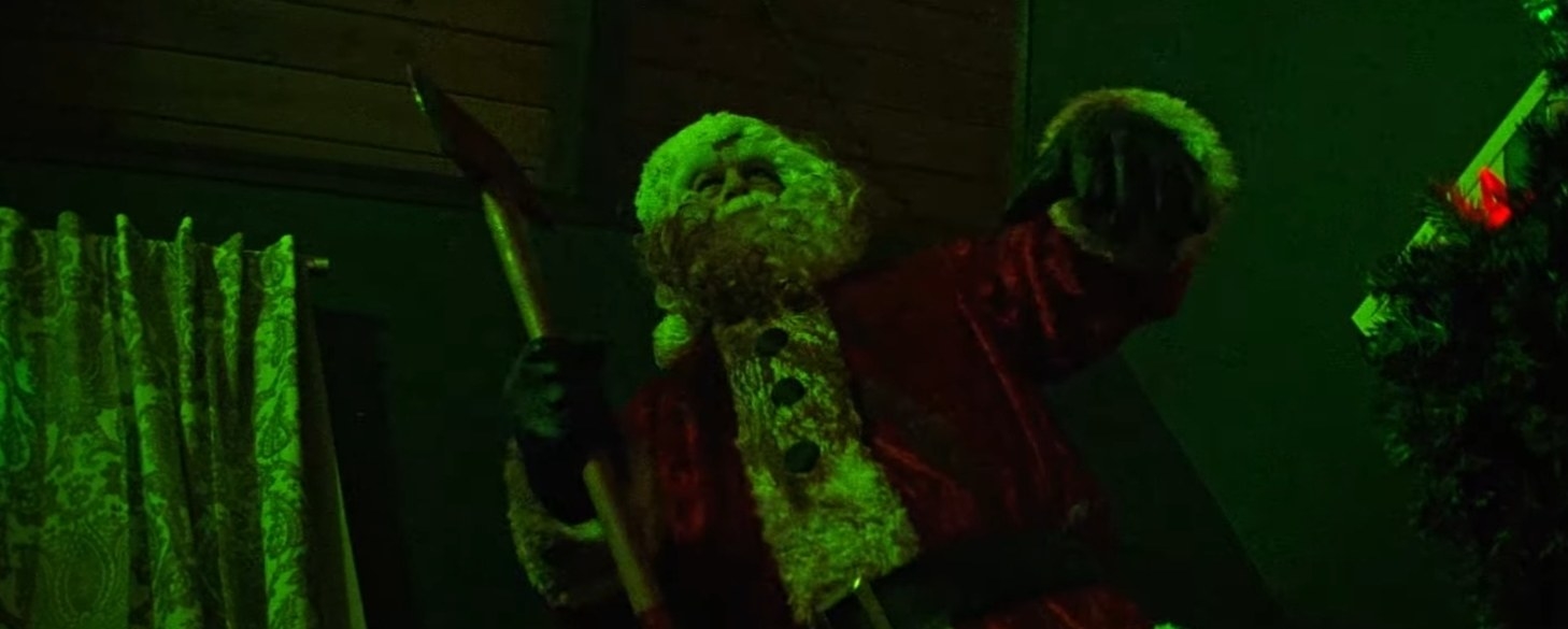 A blood-covered Santa Claus, illuminated by green lights, wields an axe