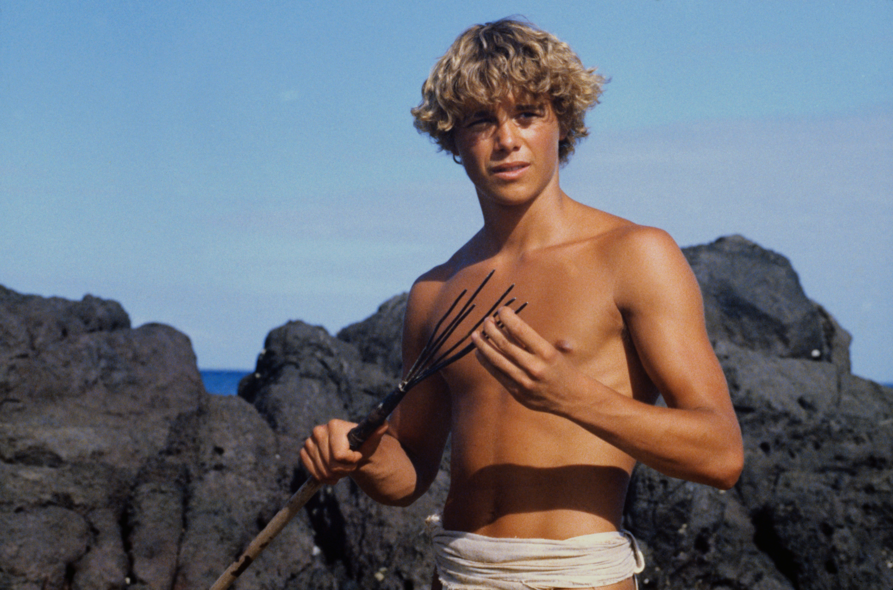 Richard on the beach holding a spear