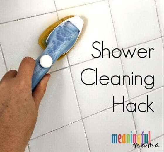 Blogger&#x27;s photo of a hand cleaning a shower with a dish brush