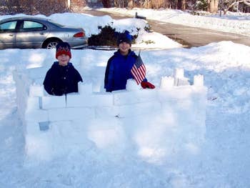 Two children pose with the snow fort they built using the mold