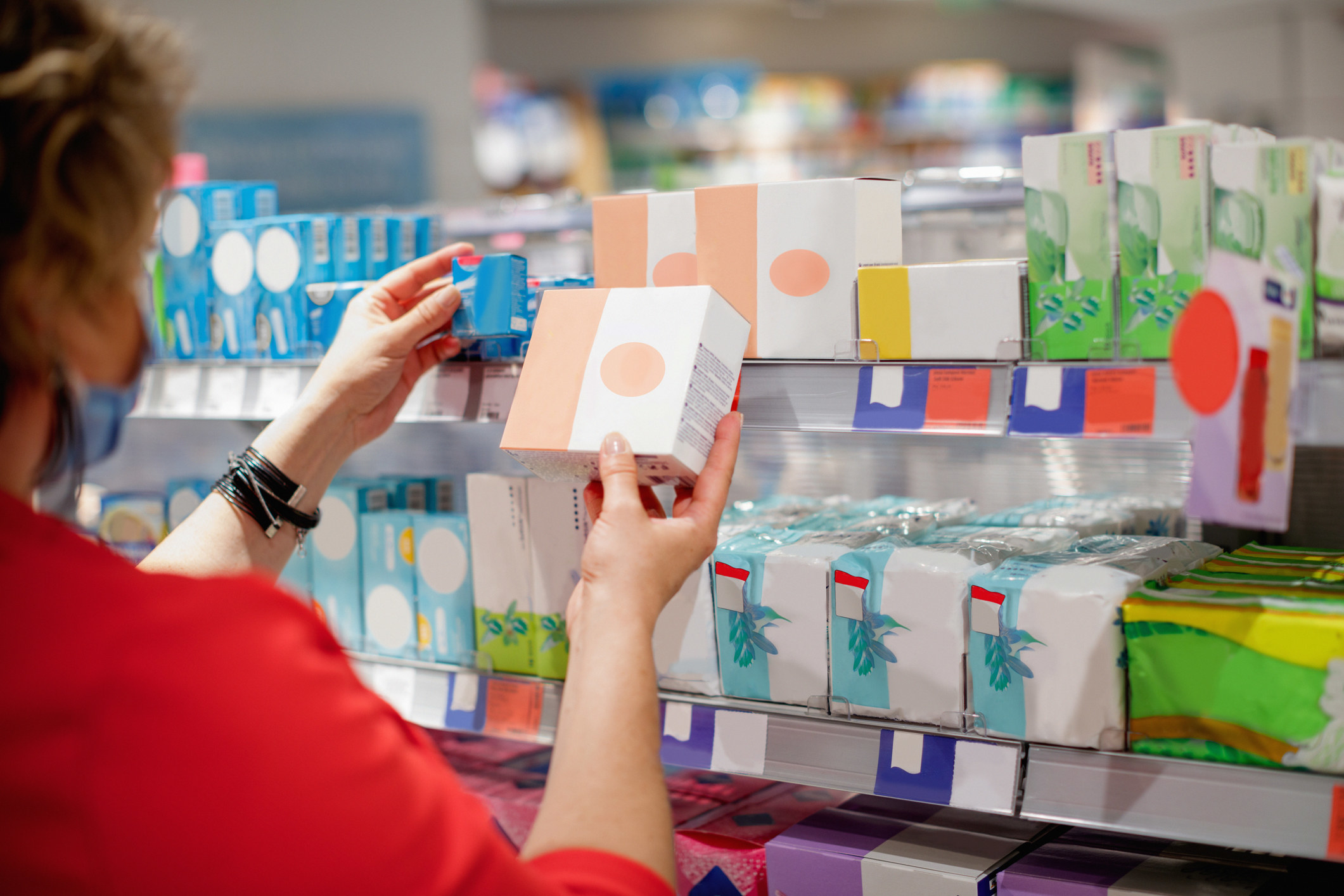 Woman picking out feminine hygiene products in an aisle at the store