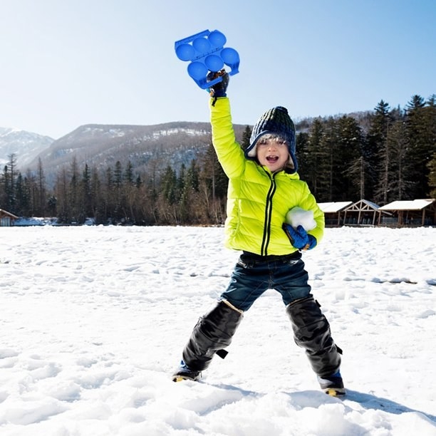 Kid in the snow holding snowball maker