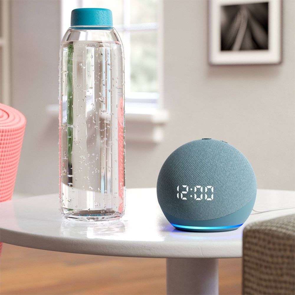 blue Amazon Echo Dot on a side table next to a water bottl