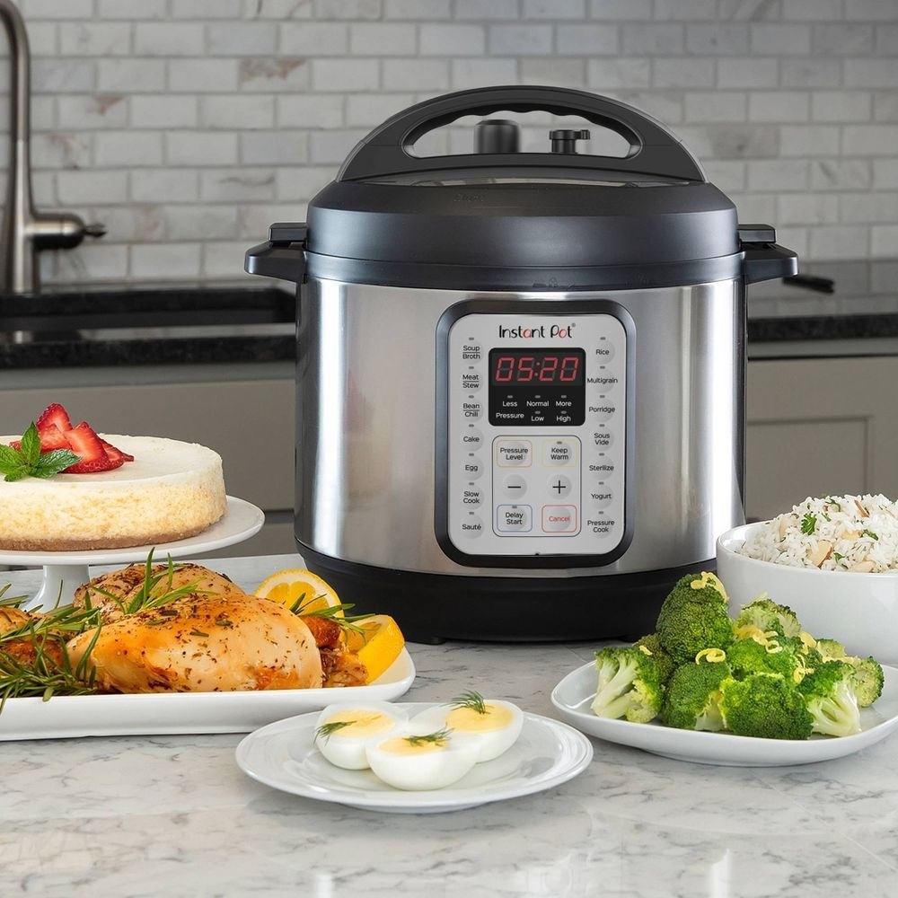 instant pot on a counter next to plates of food