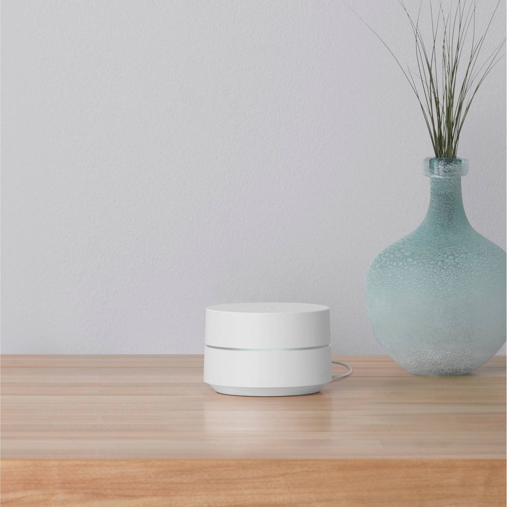 white, cylindrical Google WiFi mesh router on a table
